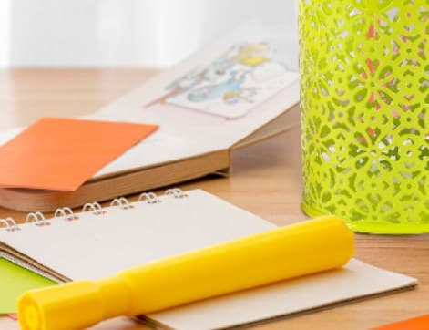 Bright green hollow-pattern mesh pen holder on a desk with stationery